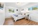 Bright bedroom featuring two windows, hardwood floors, and a white bed with decorative pillows at 6506 Lee St, Arvada, CO 80004
