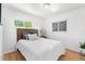 Cozy bedroom with hardwood floors, a wooden headboard, two windows, and a nightstand with a lamp and plant at 6506 Lee St, Arvada, CO 80004