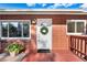 Charming brick home featuring a bright white front door adorned with a wreath and a welcoming 'hello' mat at 6506 Lee St, Arvada, CO 80004