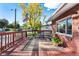 Inviting front porch of a red brick home is complete with chairs, rug, and flower pots for a relaxing setting at 6506 Lee St, Arvada, CO 80004