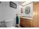 Cozy powder room featuring a toilet and wooden vanity with framed mirror and light at 14447 Madison St, Thornton, CO 80602