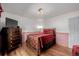 Bedroom with hardwood floors, red buffalo plaid bedspread, dresser and tv at 14447 Madison St, Thornton, CO 80602