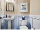 Charming powder room with blue wainscoting, a pedestal sink, and coastal decor at 5192 Sedona Dr, Parker, CO 80134