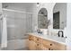 Well-lit bathroom featuring a double vanity, arched mirrors, and glass-enclosed shower at 4500 E Louisiana Ave, Denver, CO 80246