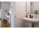 Stylish half bathroom featuring a pedestal sink, modern faucet, and views into the open-concept kitchen at 4500 E Louisiana Ave, Denver, CO 80246