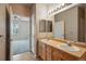 Bright bathroom featuring double sinks, wood cabinets, and neutral tile flooring and access to bedroom at 9557 W San Juan Cir # 306, Littleton, CO 80128