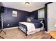 This bedroom features a full sized bed, wood-look floors, and navy painted walls at 715 Zang St, Lakewood, CO 80401