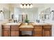 Bright bathroom with double sink vanity, granite countertop, and a large framed mirror with decorative lighting at 7965 S Titus Ct, Aurora, CO 80016