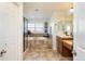 Primary bathroom featuring dual sinks, stone tile, soaking tub, and a separate glass shower enclosure at 7965 S Titus Ct, Aurora, CO 80016