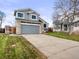 A two-story home featuring gray siding, stone accents, a two-car garage, and a well-kept front lawn at 4010 E 129Th Way, Thornton, CO 80241