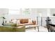 Bright living room featuring a leather couch, many windows, and a green accent chair at 1617 S Quitman St, Denver, CO 80219