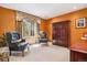 Cozy bedroom with orange walls, armchairs, a large window with decorative curtains, and a wooden armoire at 18971 Shadowood Dr, Monument, CO 80132