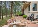 Charming stone walkway to home's entrance with a view of surrounding natural landscape and mature trees at 18971 Shadowood Dr, Monument, CO 80132