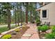 Beautiful stone walkway lined with lush landscaping leading to a home surrounded by a tranquil forest at 18971 Shadowood Dr, Monument, CO 80132
