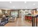 Open-concept living room and kitchen area with hardwood floors, comfortable seating, and a breakfast bar with red stools at 18971 Shadowood Dr, Monument, CO 80132