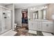 Bathroom featuring double sinks, white cabinetry, and a glass-enclosed shower, plus a walk-in closet at 6833 Longpark Dr, Parker, CO 80138