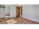 Spacious bedroom with hardwood flooring, fresh white walls, closet with mirrored door, and a paneled wooden door at 9386 W Geddes Pl, Littleton, CO 80128