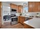 Well-lit kitchen featuring stainless steel appliances and wood cabinets, with a view into the dining area at 9386 W Geddes Pl, Littleton, CO 80128