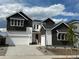 New construction, two-story home showcasing white and dark siding, with a two-car garage and well-manicured landscaping at 16521 Black Rose Cir, Parker, CO 80134
