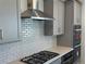 Modern kitchen featuring stainless steel hood and oven, white subway tile backsplash, and light gray cabinetry at 9354 Quartz St, Arvada, CO 80007