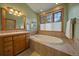 Bright bathroom featuring a tub, wooden cabinets, and a large window with a view at 31028 Big Bear Dr, Evergreen, CO 80439