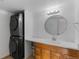 A bathroom featuring a stacked washer and dryer, vanity, and circular mirror at 9725 E Harvard Ave # 322, Denver, CO 80231