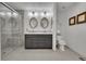 Bright bathroom featuring double vanity, modern lighting, oval mirrors, and a glass-enclosed shower at 215 Mcafee Cir, Erie, CO 80516