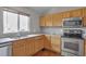 Bright kitchen featuring stainless steel appliances, granite countertops, and warm wood cabinetry at 245 Homestead Way, Brighton, CO 80601