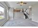 Open living room with gray carpet, ceiling fan, stairs and backyard access at 245 Homestead Way, Brighton, CO 80601