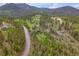 An aerial view showcasing the home's setting, surrounded by lush greenery and a winding road at 24 Pine Valley Rd, Evergreen, CO 80439