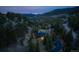 Scenic aerial view of a cozy mountain home surrounded by dense trees under a twilight sky at 24 Pine Valley Rd, Evergreen, CO 80439
