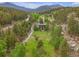 Aerial view showcasing the home amidst a sprawling green landscape with mountain views at 24 Pine Valley Rd, Evergreen, CO 80439