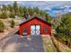 Exterior of red barn featuring a white garage door, set against a backdrop of trees and blue sky at 24 Pine Valley Rd, Evergreen, CO 80439