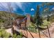 Exterior of log home connected to the road by a wooden bridge at 24 Pine Valley Rd, Evergreen, CO 80439