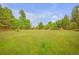 Scenic view of a sprawling, grassy property surrounded by lush, mature trees under a partly cloudy sky at 24 Pine Valley Rd, Evergreen, CO 80439
