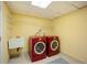 Laundry room featuring a utility sink, built-in shelving, and modern red front-load washer and dryer at 2432 S Columbine St, Denver, CO 80210