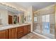 Bathroom features a double vanity, wood cabinets, tile floors, and a glass-enclosed shower at 1051 Bramblewood Dr, Castle Pines, CO 80108
