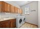 Well-equipped laundry room with wooden cabinets, sink, and a washer/dryer at 1051 Bramblewood Dr, Castle Pines, CO 80108