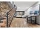 Living room featuring a stone fireplace, hardwood floors, bar seating and modern staircase at 8451 London Ln, Conifer, CO 80433