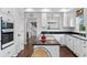 Modern kitchen with white cabinetry, black countertops, island cooktop, and view to the staircase and other spaces at 2032 W Nantucket Ct, Littleton, CO 80120