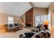 Cozy living room boasts vaulted ceilings, a striking brick fireplace, and ample natural light through shuttered windows at 8109 E Phillips Cir, Centennial, CO 80112