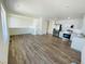 Bright, open-concept living space with wood-look floors adjacent to kitchen with stainless appliances at 45016 Sunflower Ln, Bennett, CO 80102