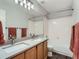 Well-lit bathroom featuring a double sink, wood cabinets, and shower with tiled walls at 19098 E Ida Dr, Aurora, CO 80015