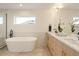 Elegant bathroom featuring a freestanding soaking tub, double sink vanity with modern fixtures and ample natural light at 2060 Eliot St, Denver, CO 80211