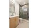 Modern bathroom featuring a glass-enclosed shower with sleek black fixtures and a light wood vanity with gold accents at 2060 Eliot St, Denver, CO 80211
