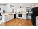 Modern kitchen with white cabinets, hardwood floors, and open layout at 13362 Marion St, Thornton, CO 80241