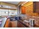 Close up of basement bar features brick accents, wood paneling, and built in sink at 6882 Moore St, Arvada, CO 80004
