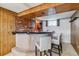 Basement bar with brick accents, wood paneling, and seating for entertaining at 6882 Moore St, Arvada, CO 80004