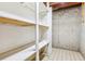 Basement storage area with built in shelving, cement wall, and concrete floor at 6882 Moore St, Arvada, CO 80004