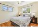 Bright bedroom featuring wood floors, two windows, and neutral colored bedding at 6882 Moore St, Arvada, CO 80004